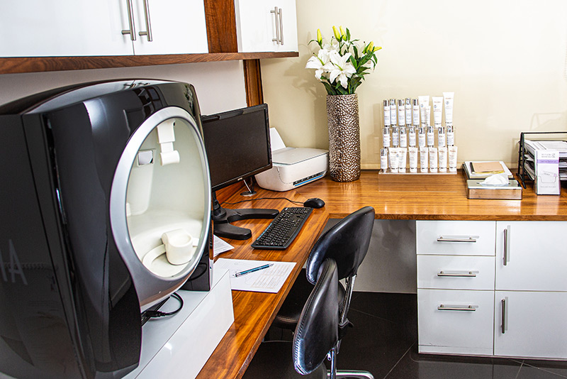 Aesthetic skin analysis room with imaging machine, products, and desktop setup.