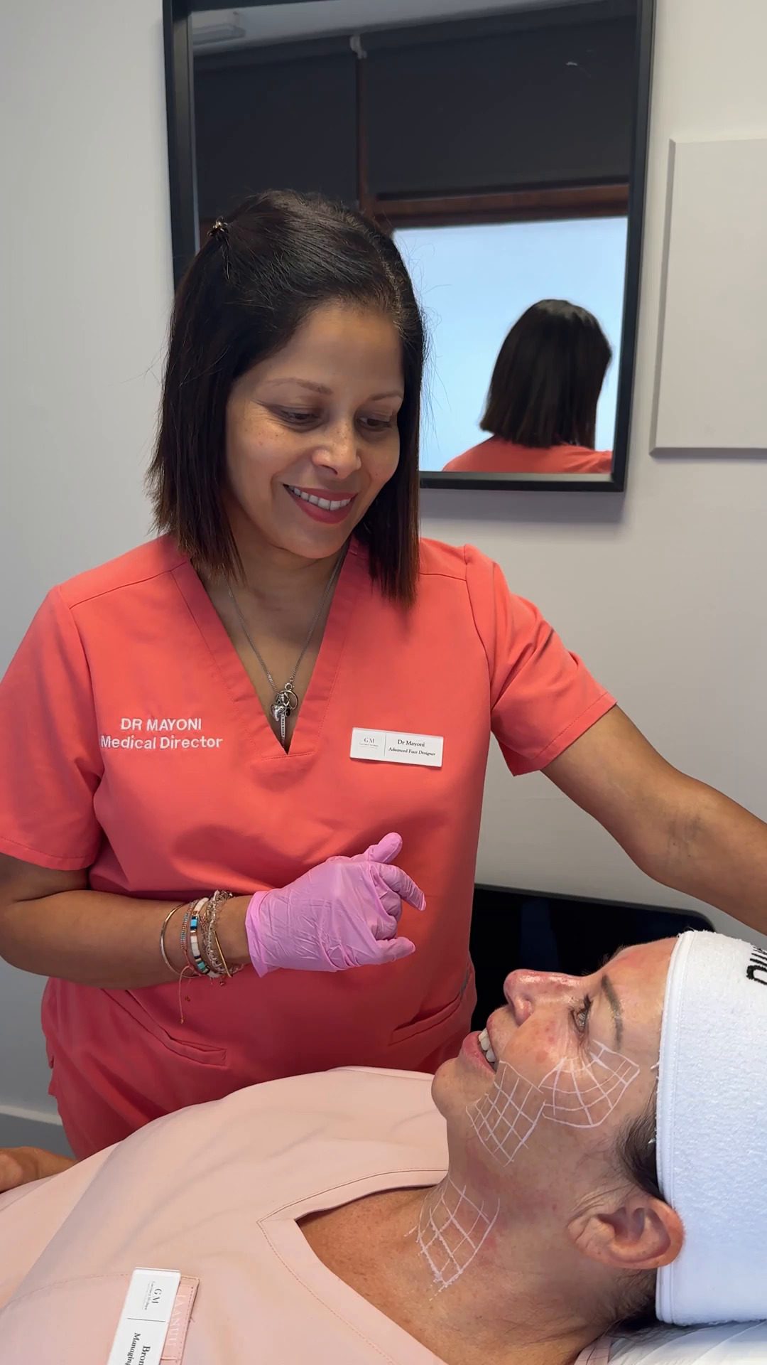 Aesthetic doctor consulting a smiling patient during facial assessment session.